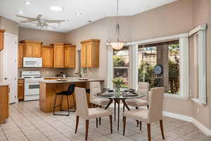 Kitchen with white appliances, light tile patterned floors, light countertops, decorative light fixtures, and a peninsula