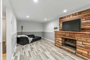 Living room featuring recessed lighting, light wood-style flooring, and a stone fireplace