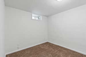 Carpeted empty room with baseboards and a textured ceiling
