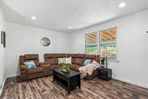 Living room with crown molding, dark wood-style flooring, and recessed lighting