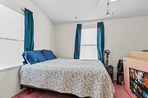 Bedroom with carpet floors, a textured ceiling, and a ceiling fan