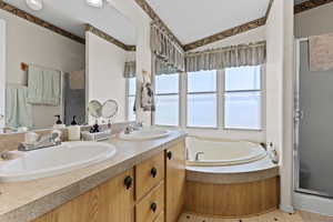 Full bath featuring a textured ceiling, a stall shower, double vanity, a garden tub, and vaulted ceiling