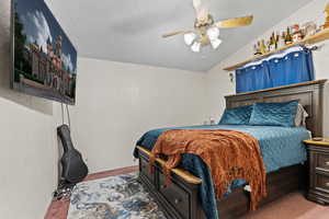 Bedroom with a textured ceiling, carpet floors, a ceiling fan, and vaulted ceiling