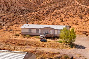 View of front of home featuring a metal roof, a wooden deck, stairway, and view of desert