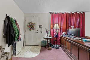 Foyer with a textured ceiling and light colored carpet