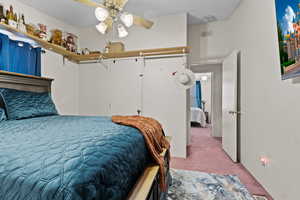 Carpeted bedroom featuring a textured ceiling and ceiling fan