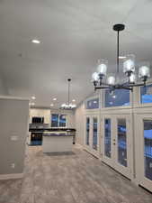 Kitchen featuring a chandelier, pendant lighting, recessed lighting, a center island, and white cabinets