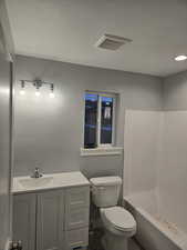 Full bath with vanity, a textured ceiling, and  shower combination