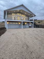 View of front facade featuring driveway, board and batten siding, stairs, an attached garage, and a patio