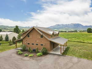 View of front facade featuring a mountain view, a front yard, and asphalt driveway