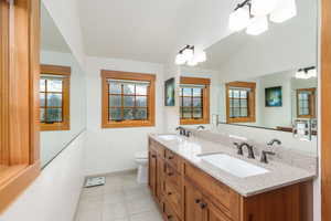 Full bathroom with light tile patterned floors, double vanity, plenty of natural light, and lofted ceiling
