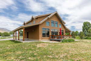 Rear view of house featuring a yard, board and batten siding, and a wooden deck