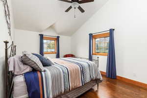 Bedroom with dark wood-type flooring, a ceiling fan, and lofted ceiling