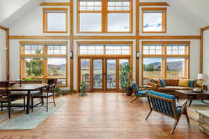 Living area with a mountain view, wood-type flooring, healthy amount of natural light, and high vaulted ceiling