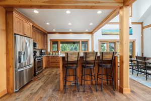Kitchen with stainless steel appliances, a kitchen bar, healthy amount of natural light, recessed lighting, and dark wood-type flooring