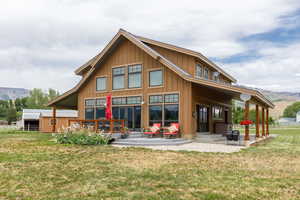 Rear view of house featuring a mountain view, board and batten siding, and a patio area