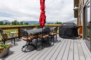 Deck with a grill, a mountain view, and outdoor dining area