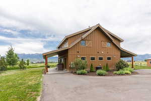 View of side of property featuring a mountain view, board and batten siding, and a lawn