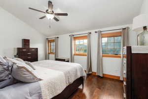 Bedroom featuring dark wood-type flooring, lofted ceiling, multiple windows, and ceiling fan