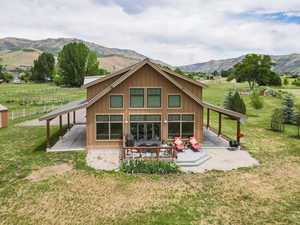 Back of house featuring a view of rural / pastoral area, a yard, a patio area, and board and batten siding