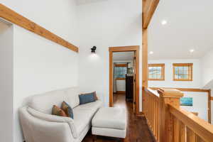 Sitting room featuring dark wood finished floors, recessed lighting, beamed ceiling, and an upstairs landing
