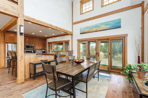 Dining area featuring light wood-type flooring, recessed lighting, a high ceiling, and french doors