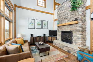 Living area with wood finished floors, a high ceiling, and a fireplace