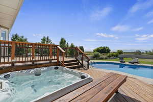 View of pool with an outdoor hot tub and a deck