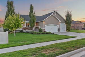 View of front of house with a front lawn, stucco siding, stone siding, and concrete driveway