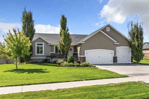 Single story home featuring a front lawn, driveway, stucco siding, and an attached garage