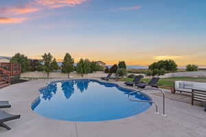 Pool at dusk with a fenced backyard, a patio area, and an outdoor hangout area