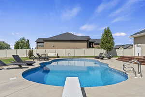 View of swimming pool with a patio area, a fenced backyard, and a diving board