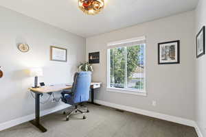 Carpeted home office featuring baseboards