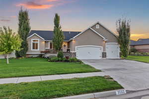 View of front facade featuring a front yard, a garage, stucco siding, and concrete driveway