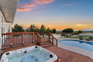 Wooden deck with an outdoor hot tub, a fenced backyard, and a patio area