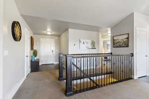 Corridor with carpet floors, a textured ceiling, and an upstairs landing