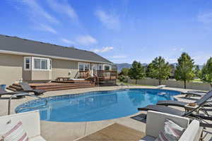 View of swimming pool with a patio, a deck with mountain view, and a diving board