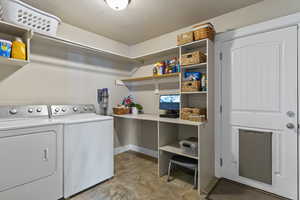 Laundry area featuring a textured ceiling, washing machine and dryer, and stone finish flooring