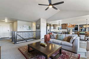 Carpeted living area featuring a chandelier, lofted ceiling, and ceiling fan