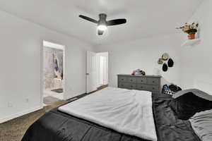 Bedroom featuring dark colored carpet, ceiling fan, and connected bathroom