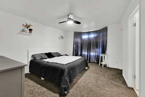 Carpeted bedroom featuring ceiling fan and baseboards