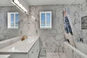 Full bathroom with tile walls, tiled shower / bath combo, and vanity