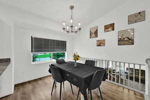 Dining space featuring light wood finished floors, vaulted ceiling, and a chandelier