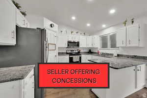 Kitchen with white cabinets, dark stone countertops, stainless steel appliances, vaulted ceiling, and recessed lighting