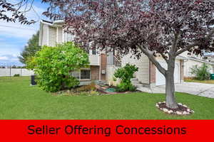 View of front facade featuring a front lawn, brick siding, and concrete driveway