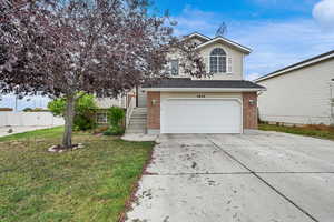View of front facade with concrete driveway, brick siding, a garage, stairs, and a shingled roof