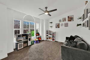 Rec room with lofted ceiling, dark carpet, and ceiling fan
