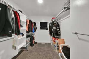 Walk in closet featuring dark colored carpet