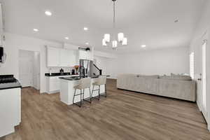 Kitchen featuring open floor plan, white cabinetry, a breakfast bar area, hanging light fixtures, and light wood-type flooring