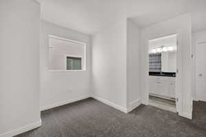 Unfurnished bedroom with dark carpet and ensuite bath